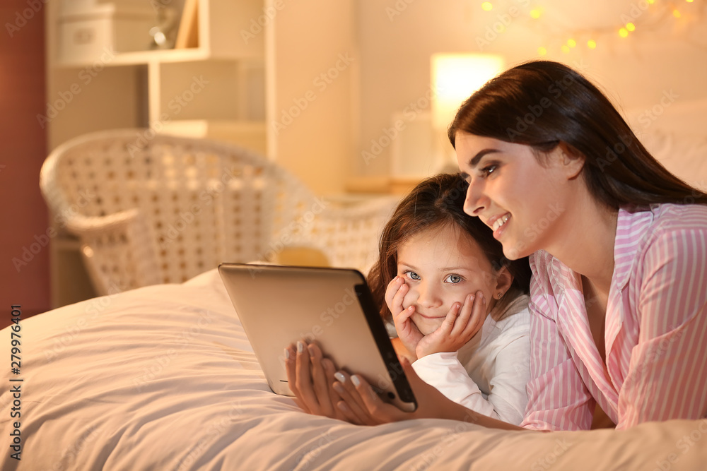 Woman and her cute little daughter with tablet computer in bedroom Woman and her cute little daughter with tablet computer in bedroom