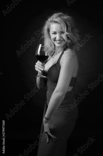 Happy attractive middle age woman in evening dress with glass of red wine.