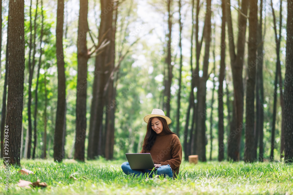 Obraz premium A woman working and typing on laptop keyboard while sitting in the park
