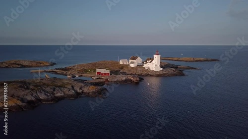 Aerial, tracking, drone shot, around the Homborsund Lighthouse, on the Store Gronningen island, on a sunny, summer evening, in Grimstad, Aust-agder, Norway photo