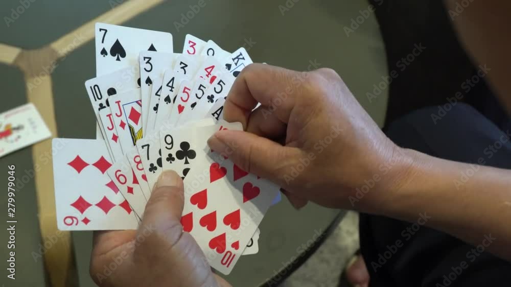 A group of people playing cards. Point of view of a man who holds playing cards in his hand.