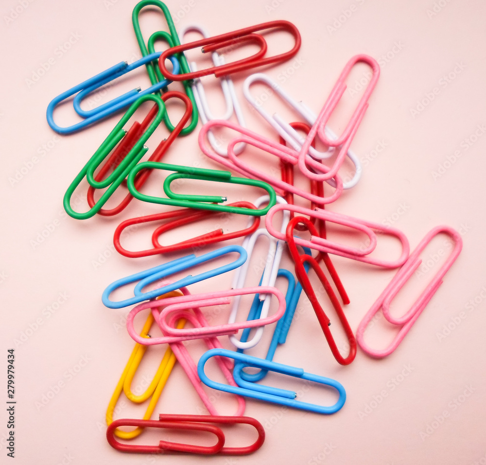 multicolored paper clips on a pink background. The concept is time to school. multicolored paper clips on a pink background. The concept is time to school.