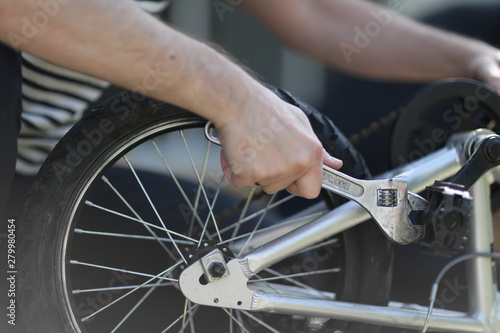 A man engaged in repairing a bicycle with a spanner in his hand