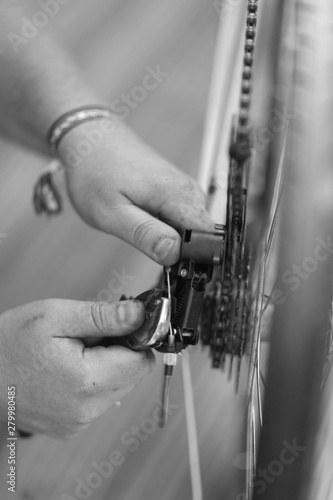 A man is engaged in repairing a bicycle wheel with a tool in his hands.