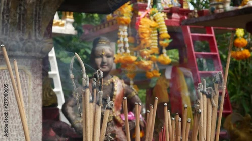 Wooden miniature guardian spirit house. Small buddhist temple shrine, colorful flower garlands. San phra phum erected to bring fortune. Traditional respect animistic rituals, pray ceremonies photo