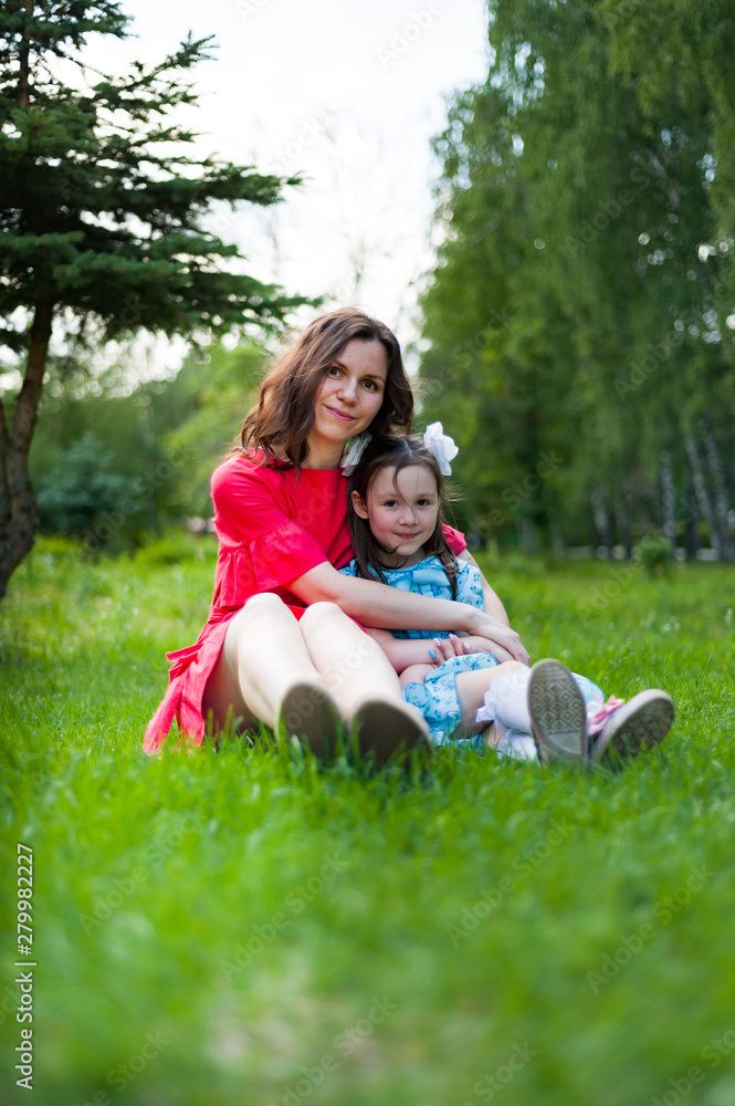 cute little girl and her mother having fun on the grass in a Sunny Park