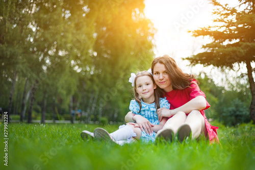 cute little girl and her mother having fun on the grass in a Sunny Park