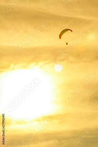sunset with paragliders pilot flying over clouds