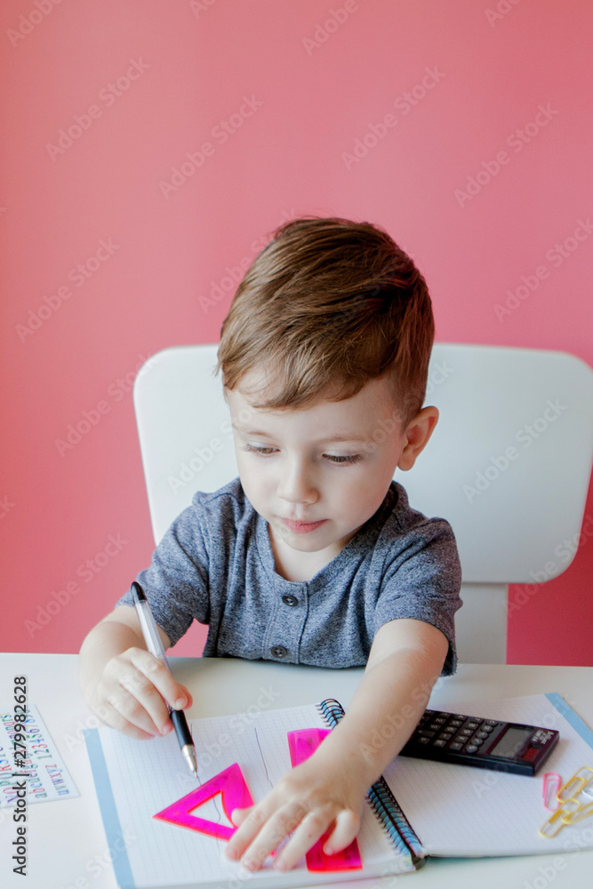 Portrait of cute kid boy at home making homework. Little concentrated child writing with colorful pencil, indoors. Elementary school and education. Kid learning writing letters and numbers Portrait of cute kid boy at home making homework. Little concentrated child writing with colorful pencil, indoors. Elementary school and education. Kid learning writing letters and numbers