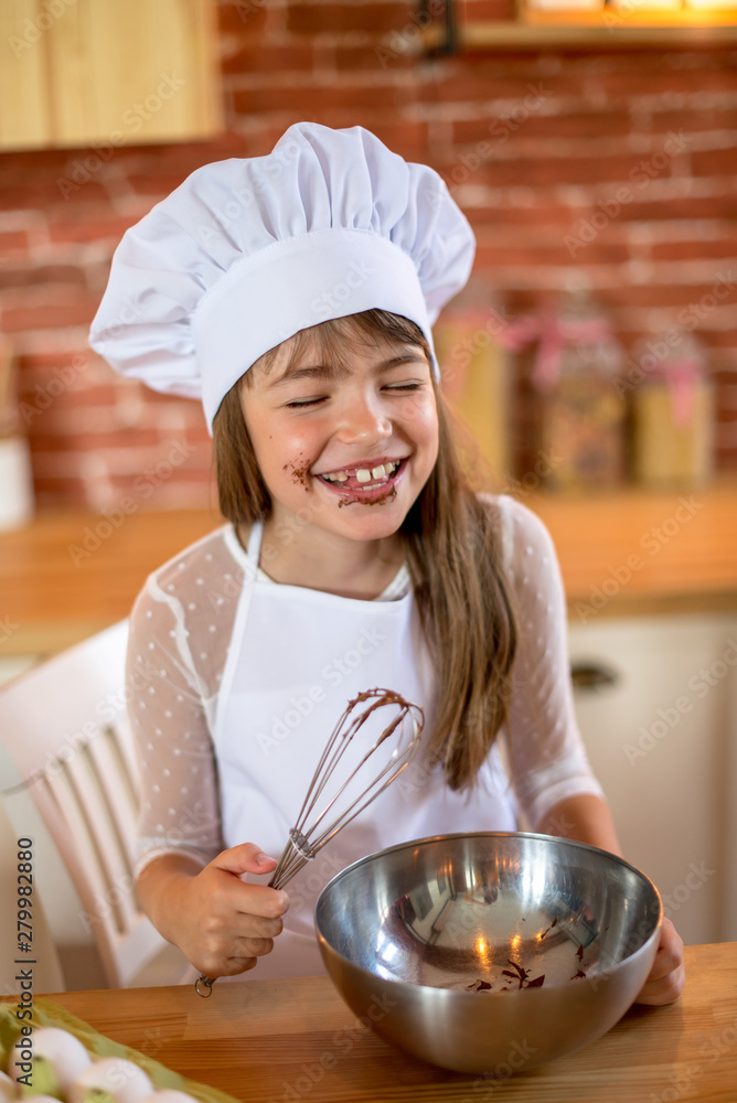 Funny chef girl cooking at kitchen. Girl of school age. Homemade food concept. Funny chef girl cooking at kitchen. Girl of school age. Homemade food concept.