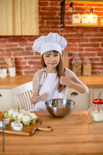 Sweet girl seven years is learning how to make a cake, in the home kitchen. Family concept
