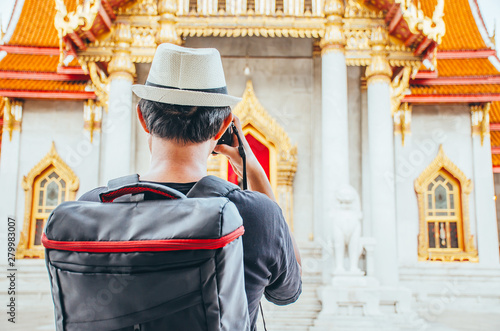 Asian man tourist taking photo with camera at Wat Benchamabophit Dusitvanaram Bangkok Thailand. Travelers take pictures with DSLR cameras. Asia tourist, Thailand. . photo