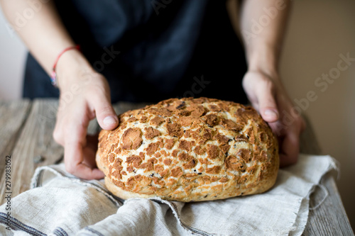 Woman holding freshly baked sourdough bread loaf