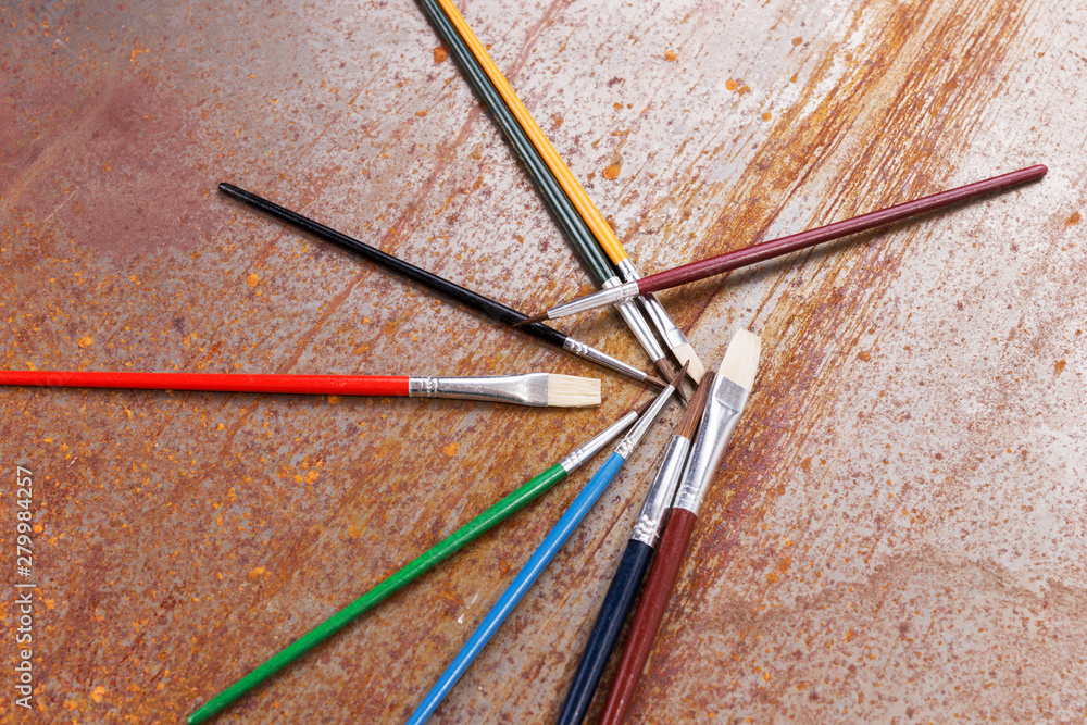 Colorful paint brushes are lying jumbled on the rusty background Colorful paint brushes are lying jumbled on the rusty background
