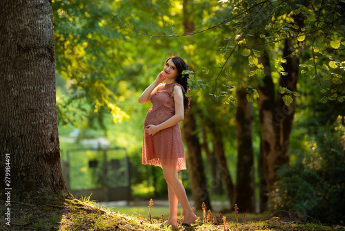 pregnant girl in dress walks through the woods
