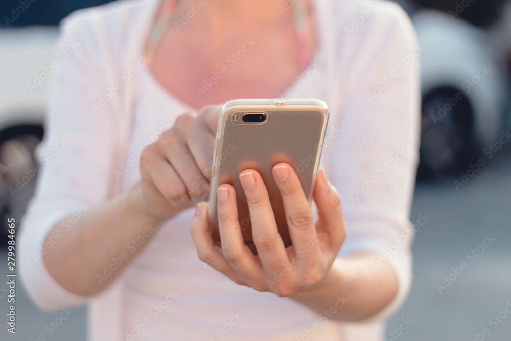 Close view of a young person holding and making use of a mobile phone or smart phone. Blurred background