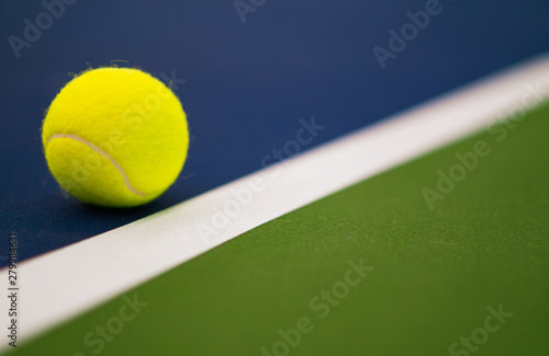 one new tennis ball near white line in blue and green hard court with copy space on right © angyim