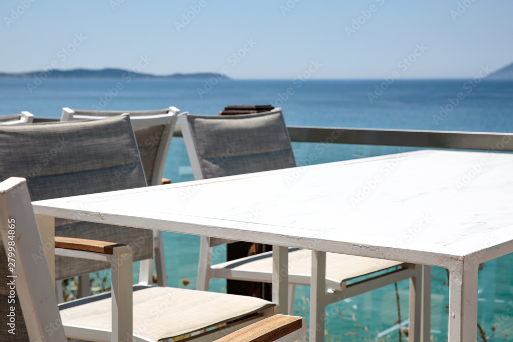 Fototapeta premium White table with chairs on the beautiful ocean view.