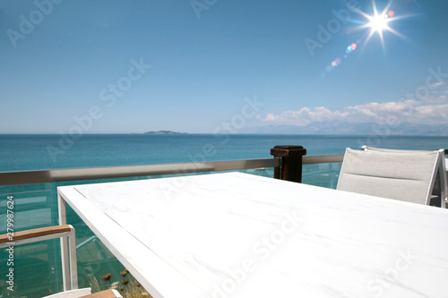 A white table background on a balcony  on a beautiful sunny blue sky and ocean view, © magdal3na