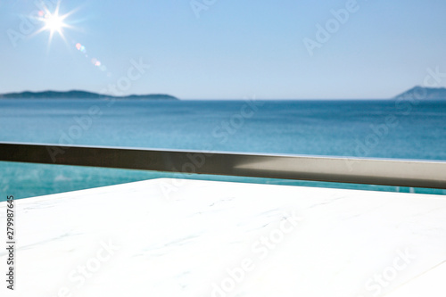 Fototapeta Naklejka Na Ścianę i Meble -  A white table background on a balcony  on a beautiful sunny blue sky and ocean view,