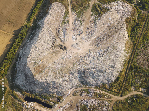 Aerial top drone view of large garbage pile, trash dump, landfill, waste from household dumping site, excavator machine is working on a mountain of garbage. Consumerism and contamination concept photo