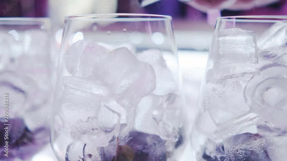 Alcohol is poured into a glass with ice. Slow motion. Bar counter nightclub. Preparation of chilled alcoholic drinks and cocktails. Alcohol is poured into a glass with ice. Slow motion. Bar counter nightclub. Preparation of chilled alcoholic drinks and cocktails.