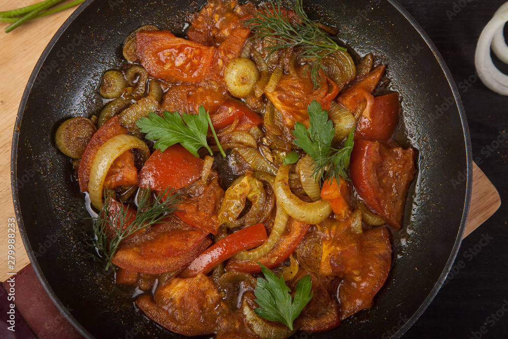 fried tomatoes with onions and parsley in a pan close-up. View from above. fried tomatoes with onions and parsley in a pan close-up. View from above.