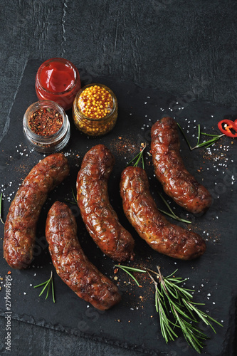 Baked sausages on a stone board. Appetizing fried sausages.