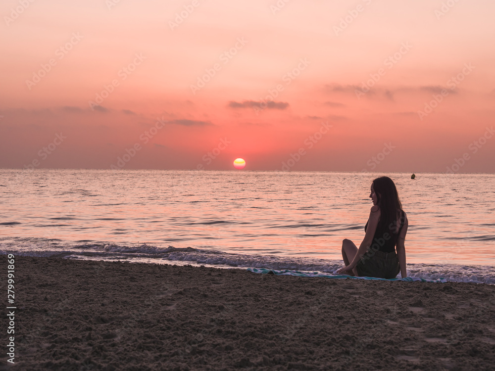 Fototapeta premium young girl on the beach watching the sunset