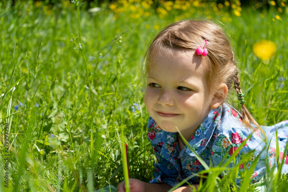 Portrait of a girl of 4 years on a green lawn. Girl on the grass in the park Portrait of a girl of 4 years on a green lawn. Girl on the grass in the park