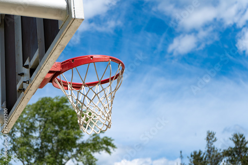 Basketball backboard with a ring on the street and blue sky