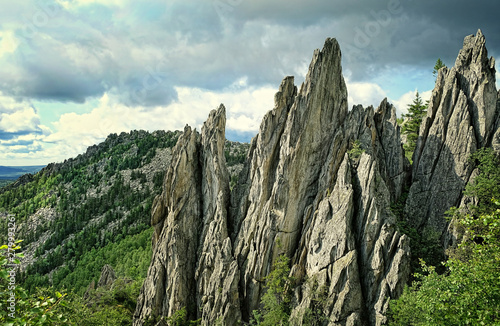 Natural landscape mountain rocks, slopes of Southern Urals. Beautiful view from top of mountain in Urals, rock "Feathers" in foreground. theme for travel backdrop design. national Park Taganay, Russia