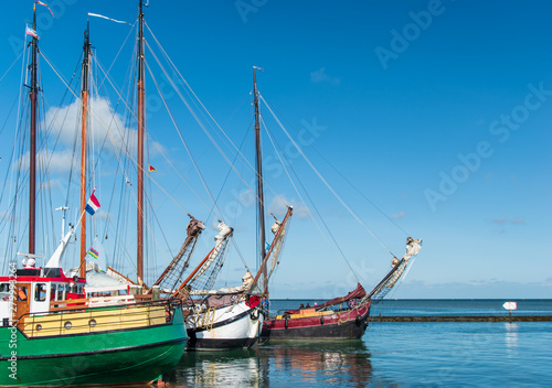 Three sailboats in a row in blue water with blue sky above it. Terschelling, The Netherlands, Europe. photo