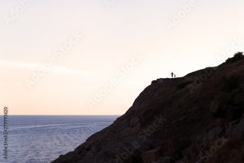 sunset over the sea and mountains, people silhouettes on the top