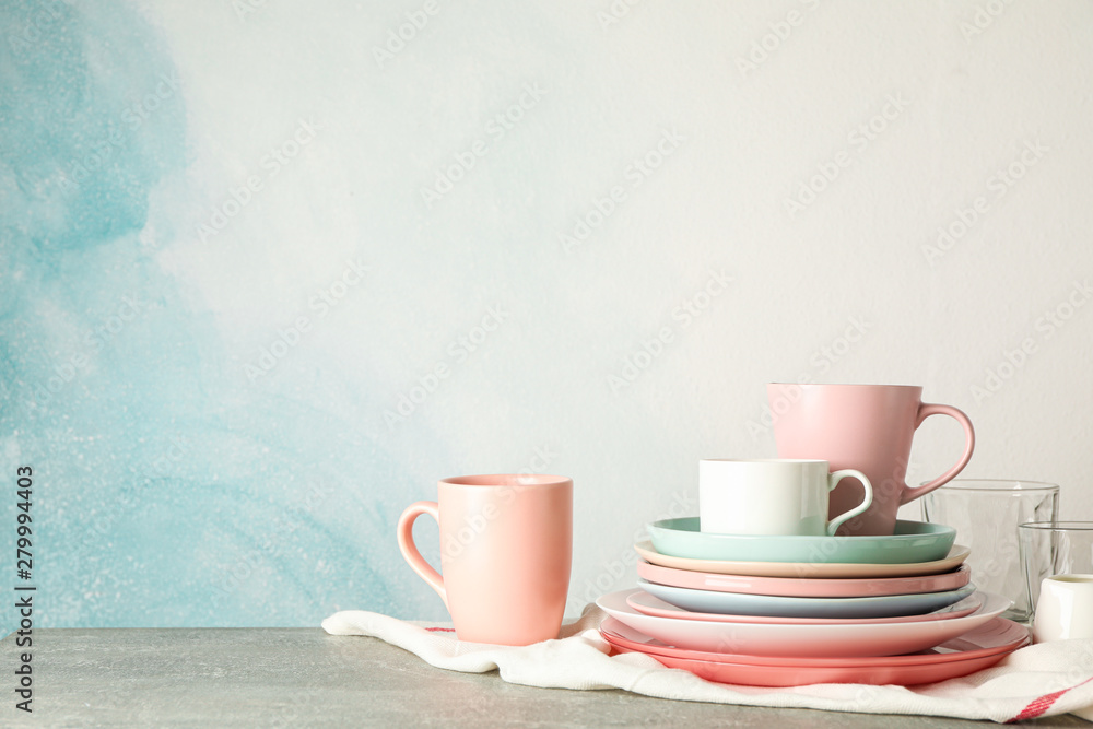 Color plates and cups stacked on grey table, space for text - obrazy, fototapety, plakaty 