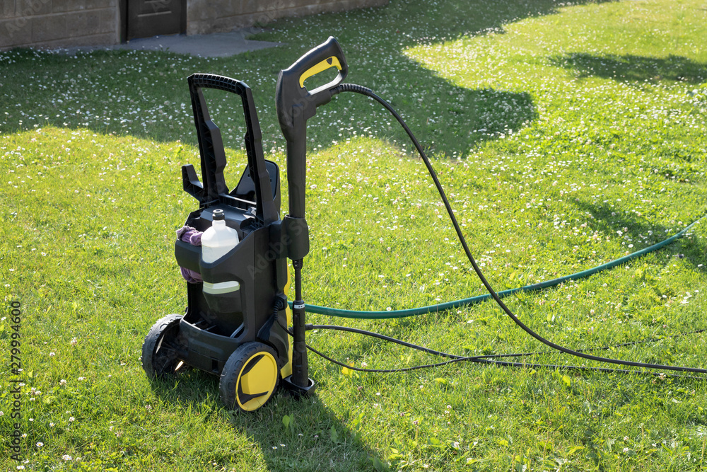 mini home pressure washer for cleaning the car on the background of green lawn mini home pressure washer for cleaning the car on the background of green lawn