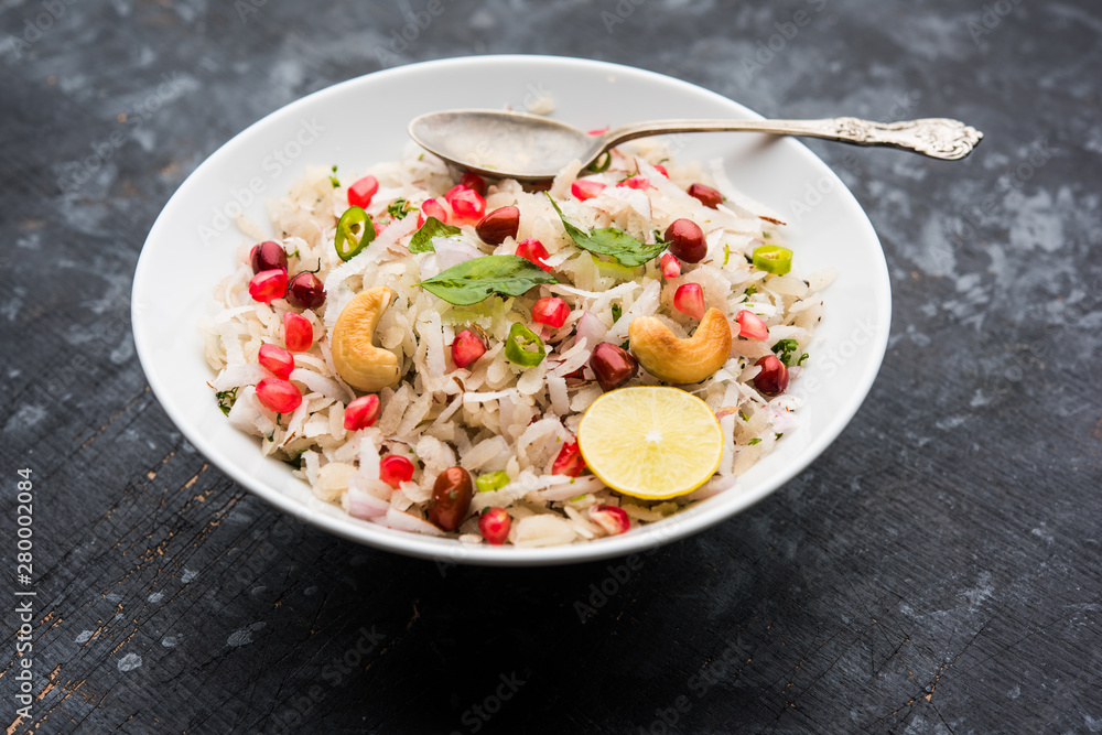 Dapde Pohe is a typical Maharashtrian breakfast, made with thin variety of poha and fresh coconut with chilli, peanuts and nuts. served in a bowl or plate. selective focus Dapde Pohe is a typical Maharashtrian breakfast, made with thin variety of poha and fresh coconut with chilli, peanuts and nuts. served in a bowl or plate. selective focus