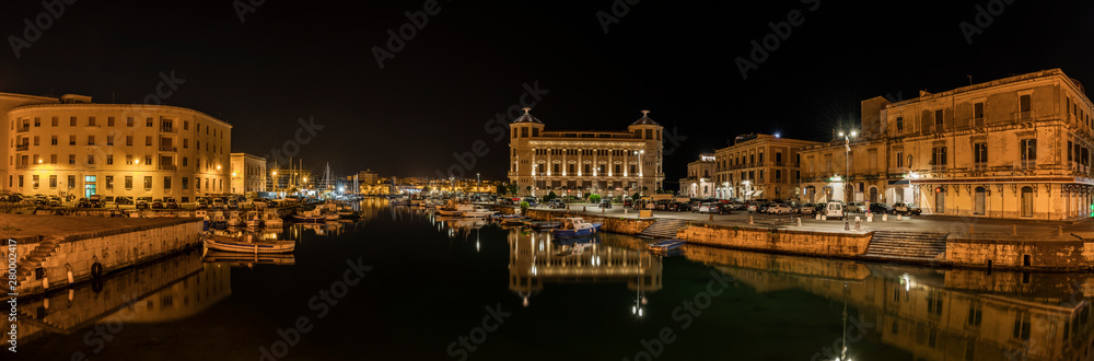 Night panoramic view over the island Ortygia and its harbour with boats by night, city of Syracuse, Sicily, south Italy