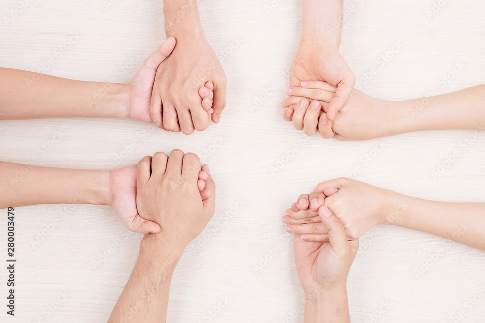 Fototapeta premium Close-up of young people sitting at the table and holding hands they support each other or playing in some game