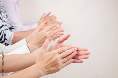 Close-up of group of business people clapping hands together while standing against the white background © DragonImages
