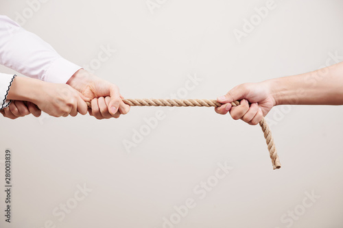 Close-up of team of people pulling the rope against the one person against the white background