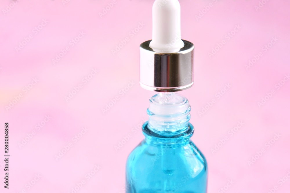 Anti aging serum in blue bottle with glass dropper on blurred pink background, selective focus. Facial liquid serum with collagen and peptides. Skincare essence for beautiful healthy skin. Soft focus Anti aging serum in blue bottle with glass dropper on blurred pink background, selective focus. Facial liquid serum with collagen and peptides. Skincare essence for beautiful healthy skin. Soft focus