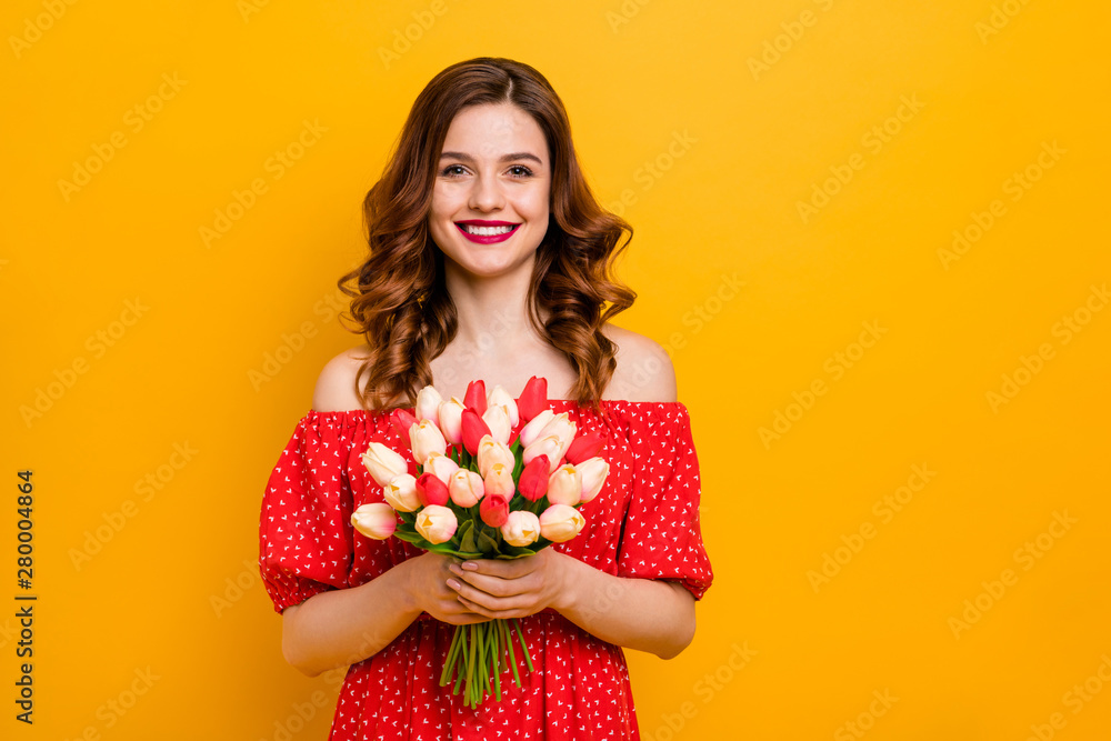 Beautiful foxy lady holding arms fresh tulips bunch wear off-shoulders dress isolated bright yellow background Beautiful foxy lady holding arms fresh tulips bunch wear off-shoulders dress isolated bright yellow background