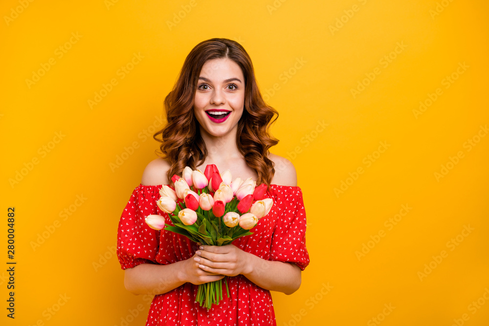 Beautiful foxy lady holding arms fresh tulips bunch wear off-shoulders dress isolated bright yellow background Beautiful foxy lady holding arms fresh tulips bunch wear off-shoulders dress isolated bright yellow background