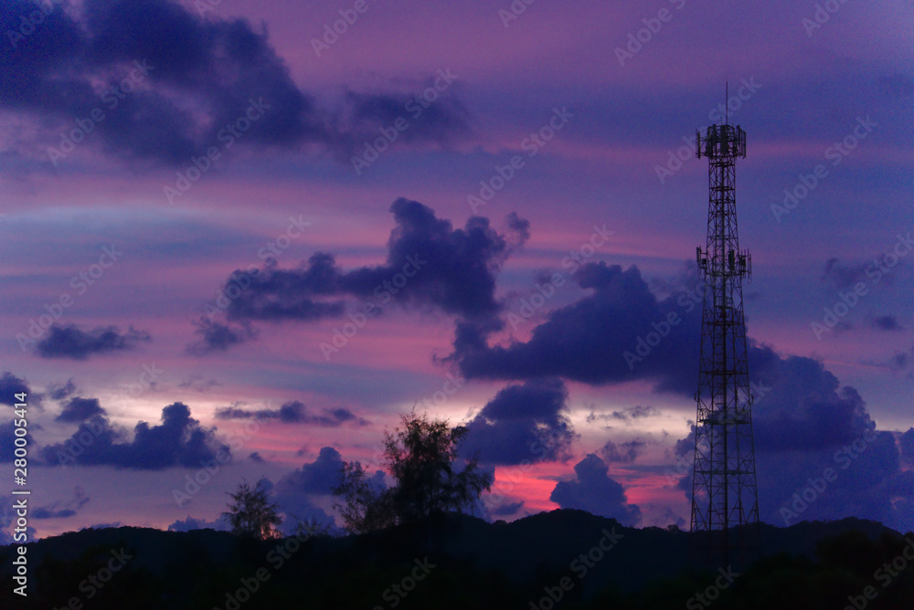 tall mobile cell phone tower on the high hill in Chantaburi, Thailand sending signal to connect people around the world in the evening when sunset with purple blue sky and clouds
