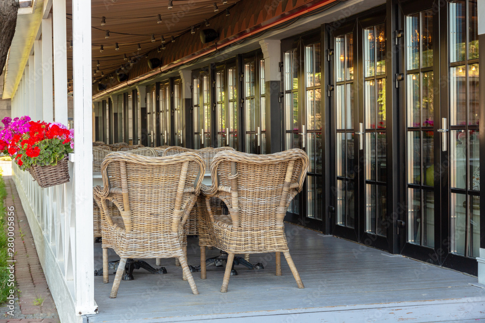 empty summer terrace of a cozy restaurant with wicker furniture and flowers empty summer terrace of a cozy restaurant with wicker furniture and flowers
