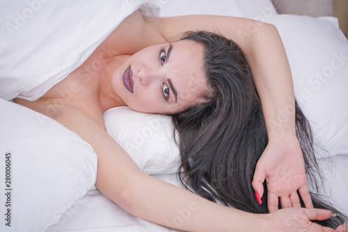 charming young brunette girl resting in her white bed