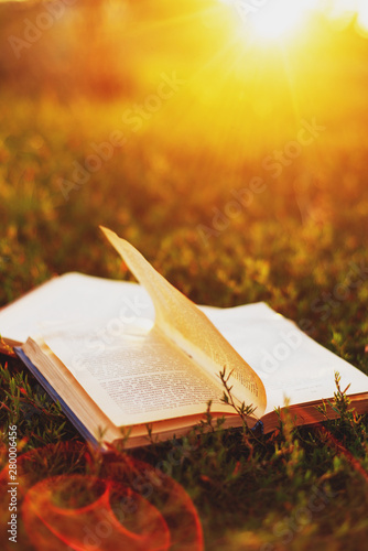 an old book on a summer meadow at sunset