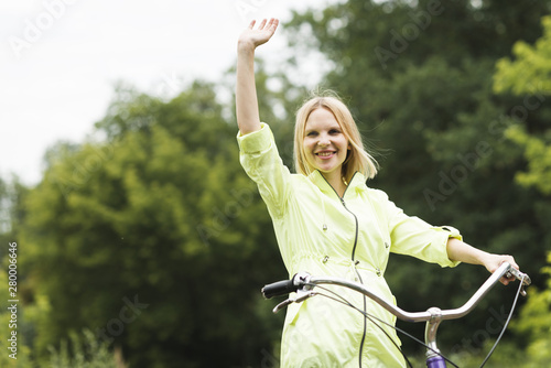 Happy woman on bicycle waving