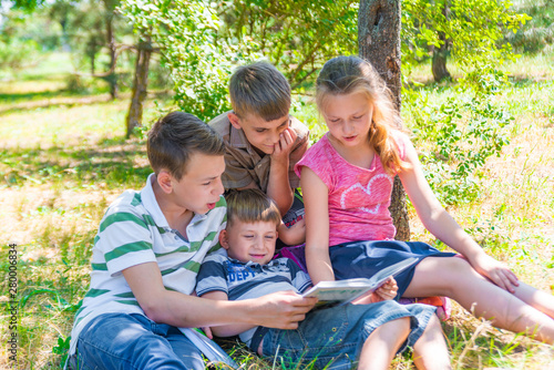 Children read a book in the park, brothers and sisters friends are studying science.